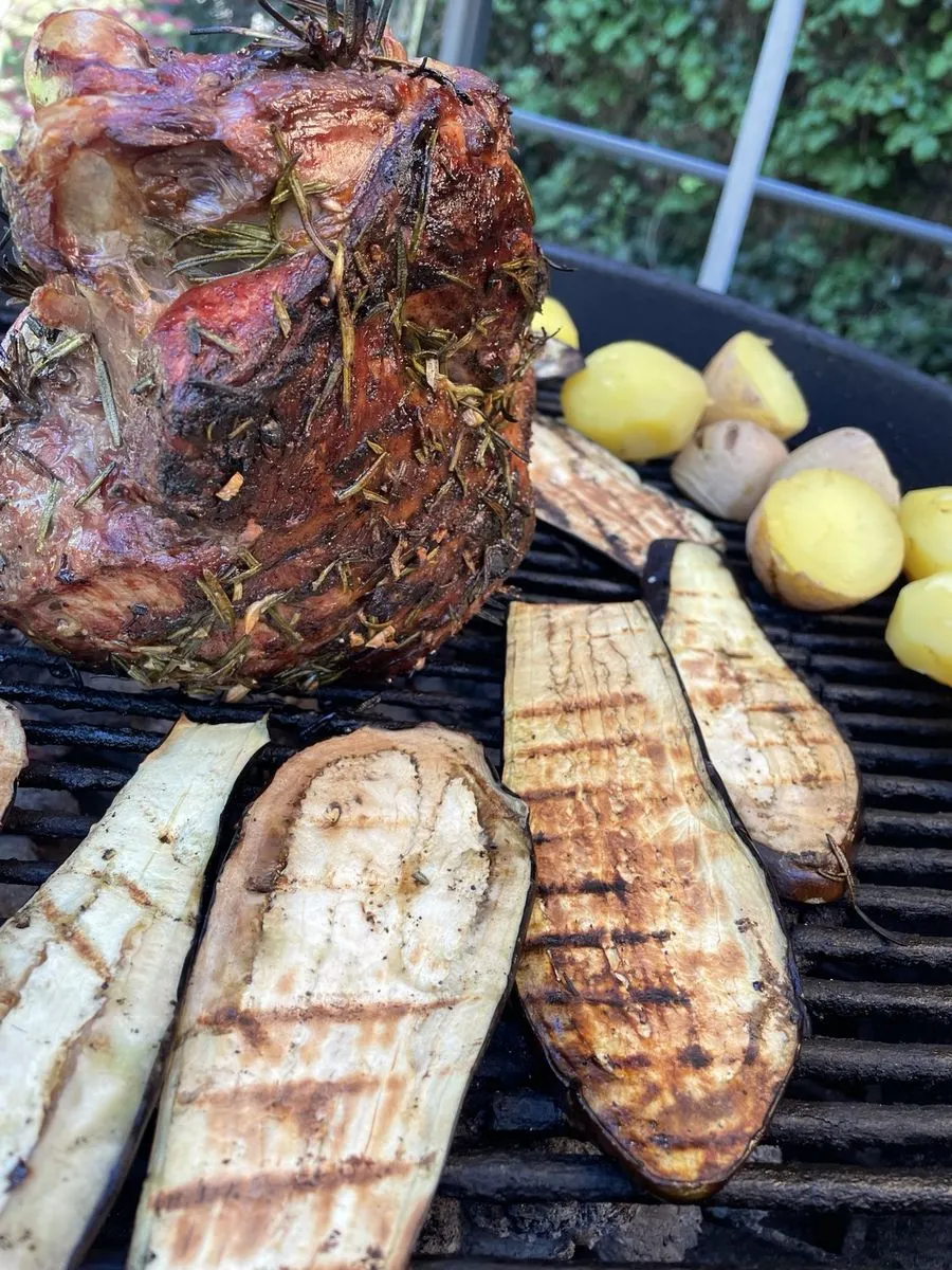 Kräuterbraten auf dem Grill, daneben gegrillte Auberginenscheiben und kleine Kartoffeln