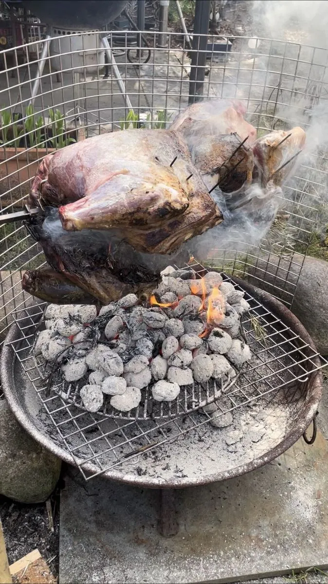Ganzes Lamm am Spieß über einer Feuerschale mit glühenden Kohlen